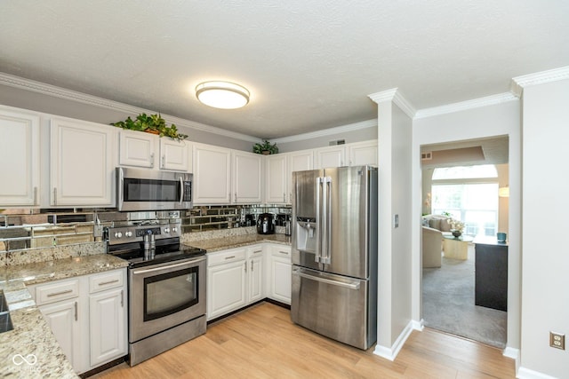 kitchen with stainless steel appliances, light stone countertops, white cabinets, and decorative backsplash