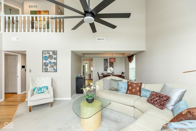 living room featuring a high ceiling, ceiling fan, and hardwood / wood-style floors