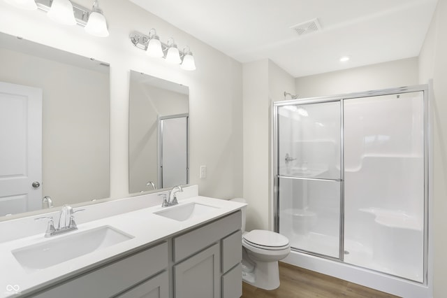 bathroom with toilet, hardwood / wood-style floors, a shower with door, and vanity