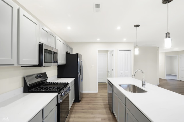 kitchen with gray cabinets, appliances with stainless steel finishes, decorative light fixtures, and sink