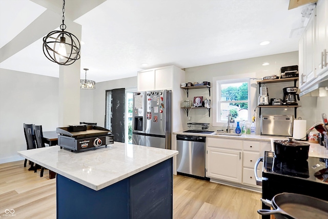 kitchen featuring stainless steel appliances, sink, decorative light fixtures, light hardwood / wood-style floors, and white cabinetry