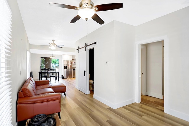 living room featuring a barn door, light hardwood / wood-style flooring, and ceiling fan