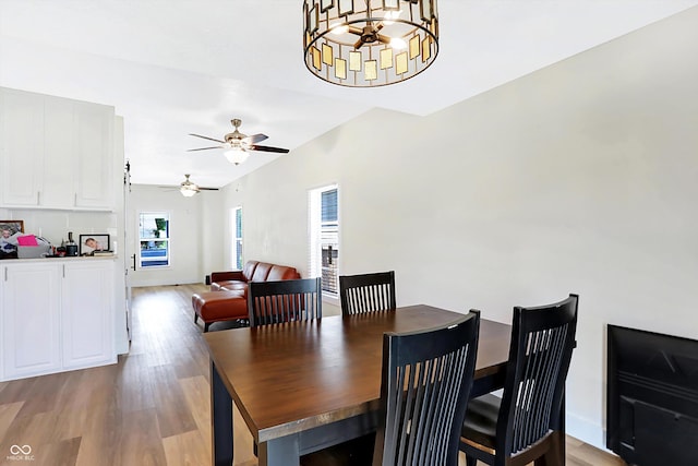 dining space with light wood-type flooring and ceiling fan with notable chandelier