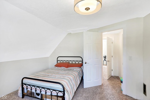 bedroom featuring carpet flooring, lofted ceiling, and a textured ceiling