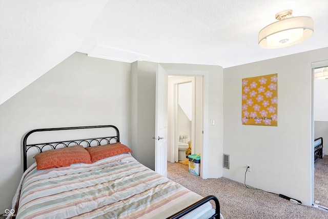 carpeted bedroom with connected bathroom and vaulted ceiling