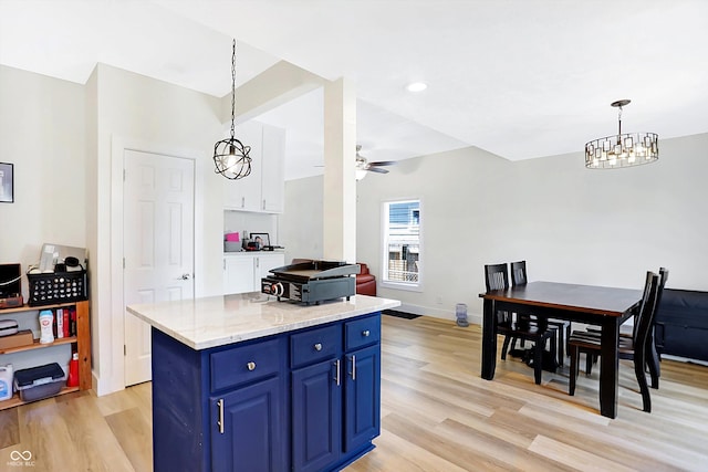 kitchen with blue cabinetry, ceiling fan, pendant lighting, light hardwood / wood-style floors, and a kitchen island