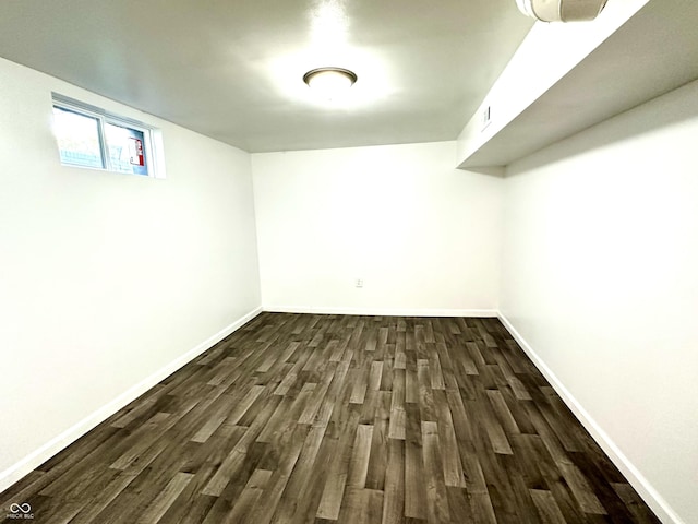 below grade area with dark wood-style floors, visible vents, and baseboards