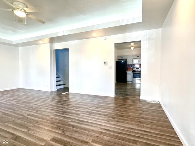 empty room with a raised ceiling, hardwood / wood-style floors, and ceiling fan