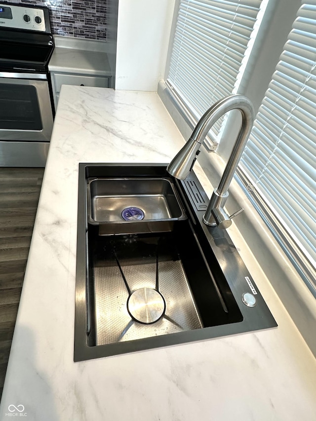 details with light countertops, stainless steel range with electric cooktop, a sink, and wood finished floors