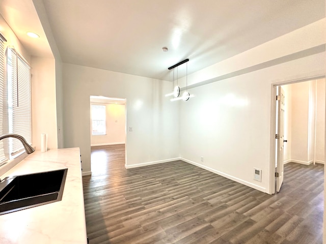 interior space with dark hardwood / wood-style floors, decorative light fixtures, light stone countertops, and sink