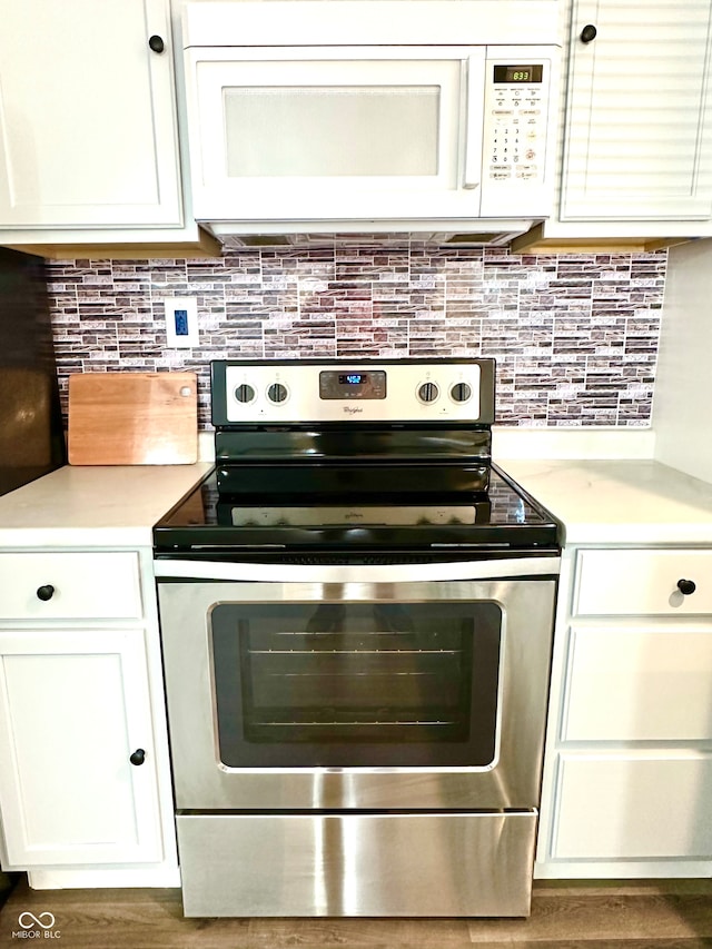 kitchen featuring white cabinets, dark hardwood / wood-style floors, decorative backsplash, and stainless steel electric range oven