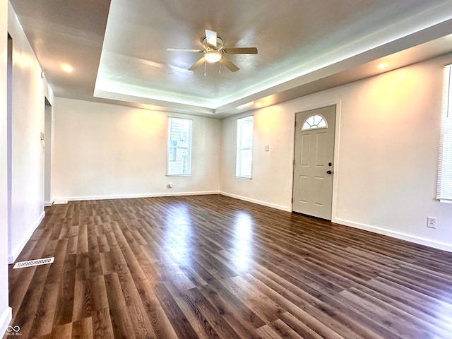 interior space featuring dark hardwood / wood-style floors, a tray ceiling, and ceiling fan