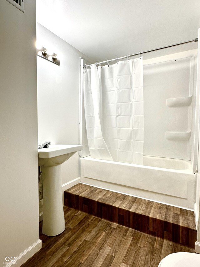 bathroom featuring toilet, hardwood / wood-style floors, and shower / tub combo with curtain