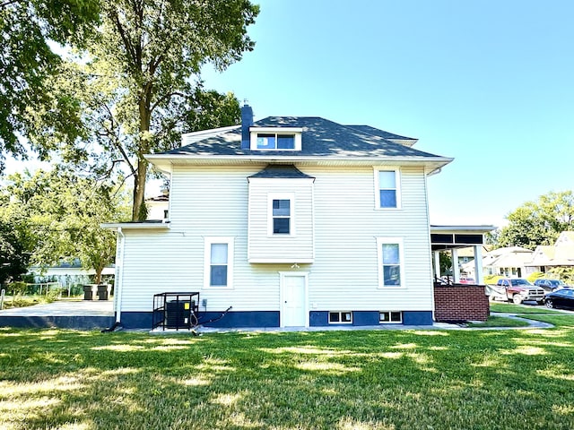 rear view of property featuring a lawn and a chimney