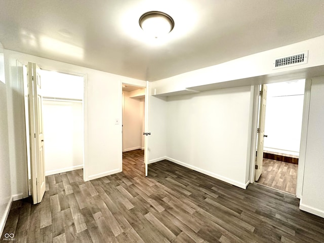 finished below grade area featuring visible vents, dark wood finished floors, and baseboards