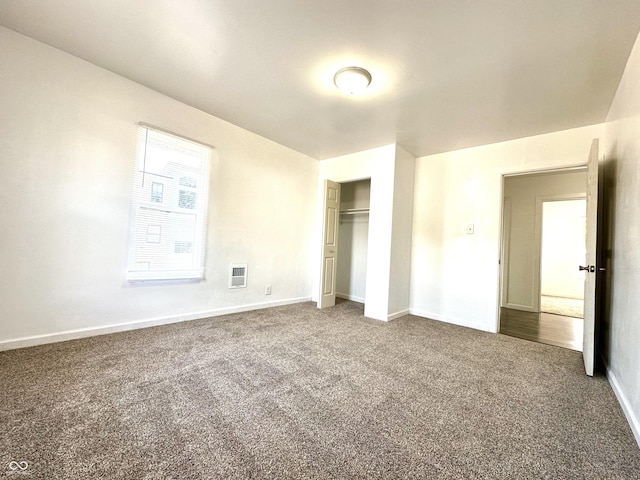 unfurnished bedroom featuring baseboards, visible vents, dark carpet, and a closet