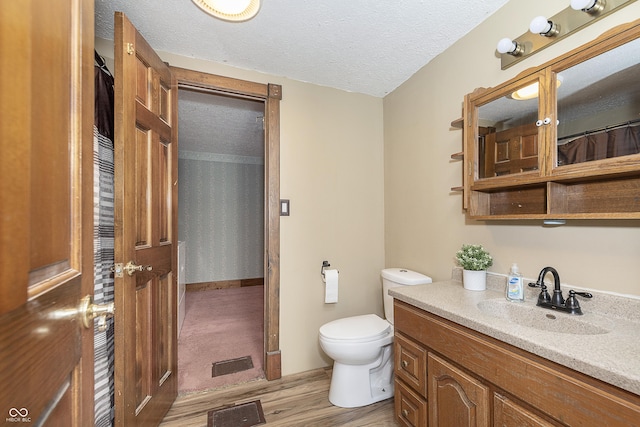 bathroom featuring vanity, wood-type flooring, toilet, and a textured ceiling