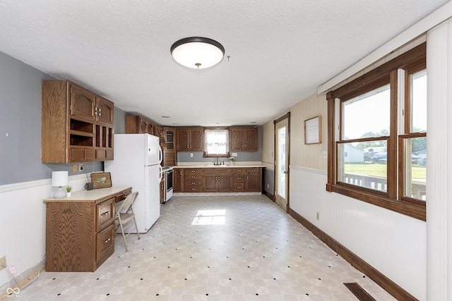 kitchen with white appliances, sink, a textured ceiling, and a wealth of natural light