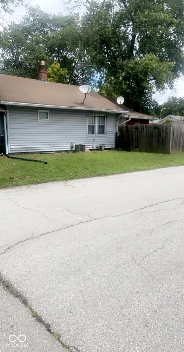 view of property exterior featuring central AC and a lawn