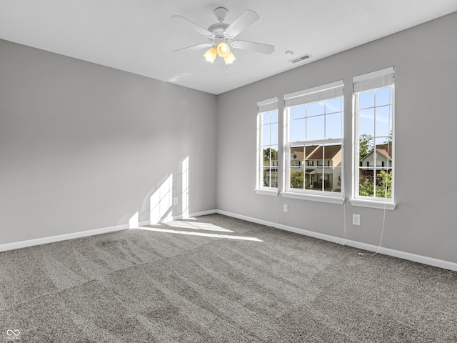 carpeted spare room featuring ceiling fan and plenty of natural light