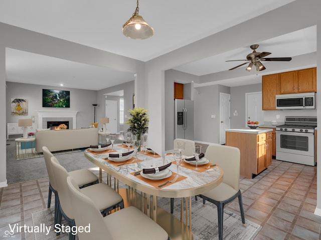 tiled dining area featuring a fireplace and ceiling fan