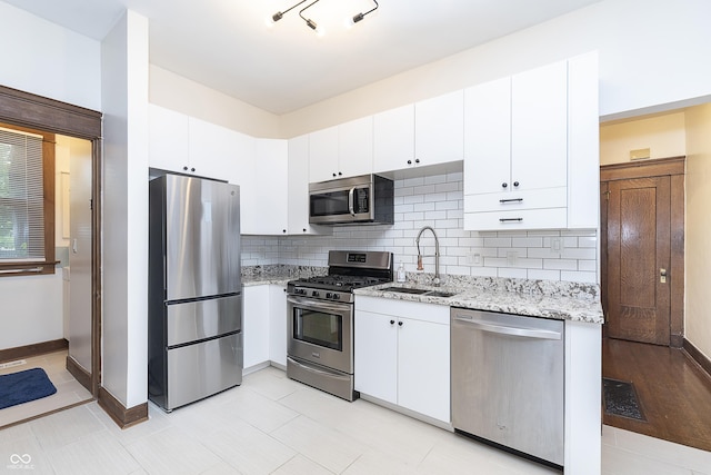 kitchen with light stone countertops, sink, white cabinets, and stainless steel appliances