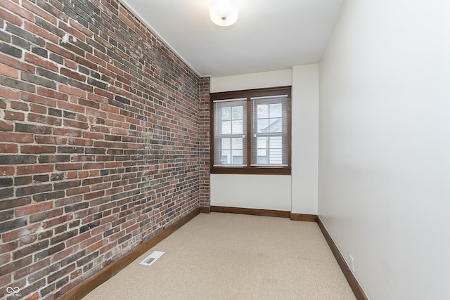 carpeted empty room with brick wall