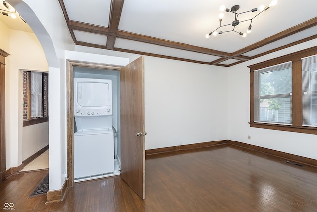 spare room featuring beamed ceiling, dark hardwood / wood-style flooring, and stacked washer and clothes dryer