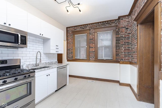 kitchen with white cabinets, stainless steel appliances, tasteful backsplash, and sink