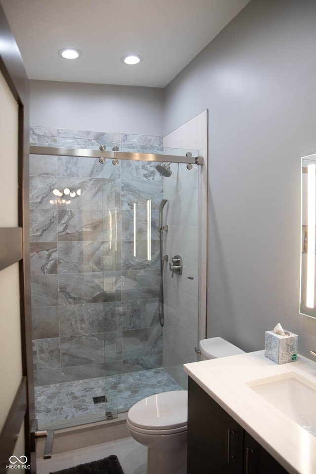 bathroom with tile patterned floors, vanity, toilet, and walk in shower