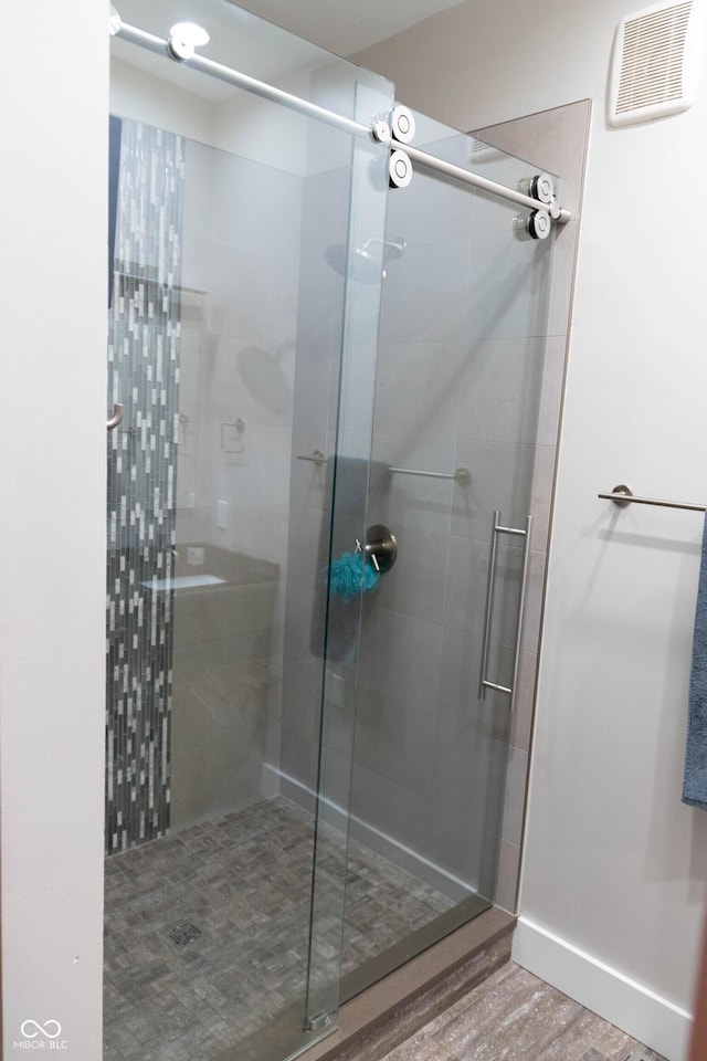 bathroom with hardwood / wood-style flooring and a shower with shower door