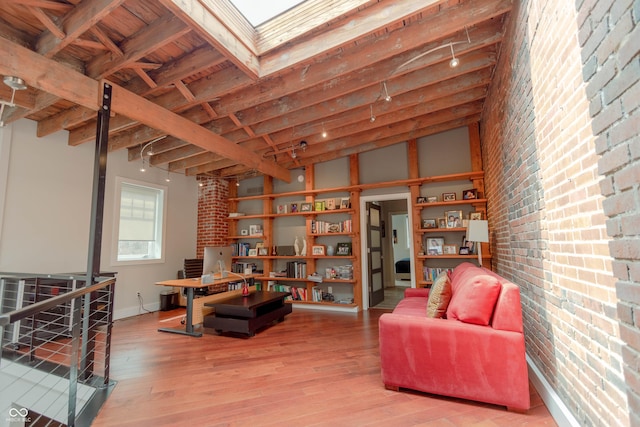 sitting room featuring wood-type flooring, vaulted ceiling with beams, wooden ceiling, and brick wall