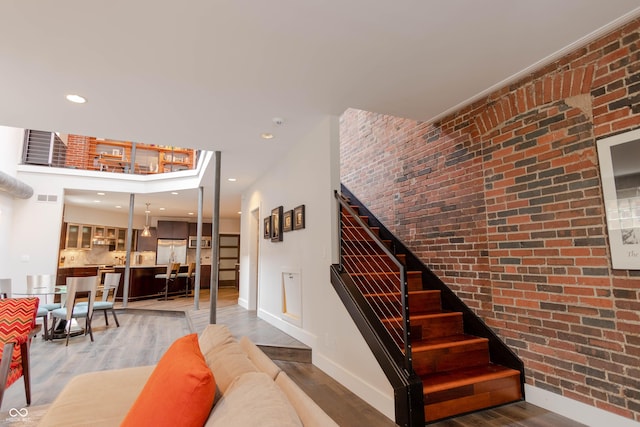 stairway with hardwood / wood-style flooring and brick wall