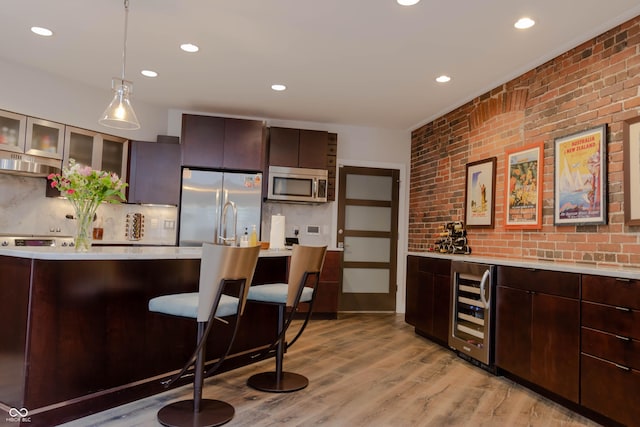 bar featuring backsplash, pendant lighting, brick wall, and appliances with stainless steel finishes