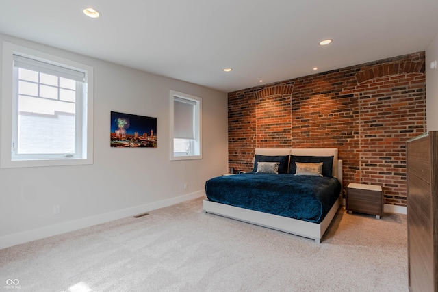 bedroom featuring light carpet and brick wall