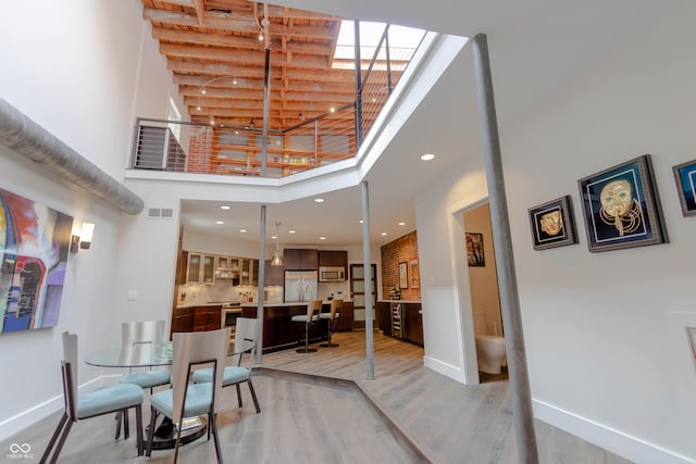 dining area with a high ceiling and light hardwood / wood-style flooring