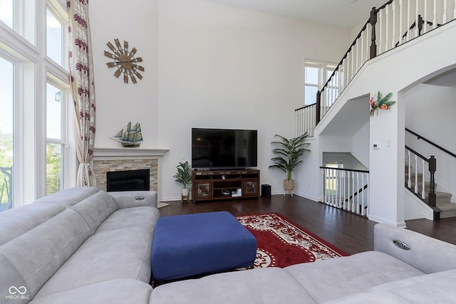 living room with dark hardwood / wood-style flooring, a fireplace, and a towering ceiling