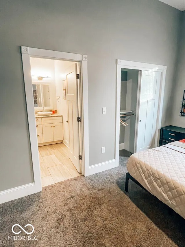 carpeted bedroom featuring connected bathroom, a closet, and sink