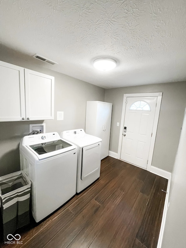 washroom featuring washer and dryer, dark hardwood / wood-style floors, cabinets, and a textured ceiling