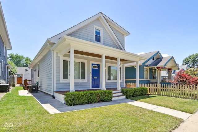 bungalow featuring a front yard, a porch, and central air condition unit