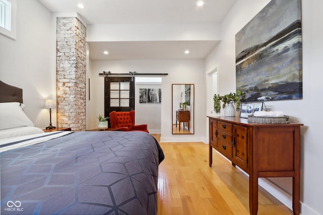 bedroom featuring a barn door, light hardwood / wood-style flooring, and multiple windows