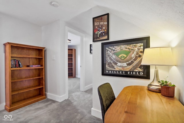 home office with lofted ceiling, carpet floors, and a textured ceiling