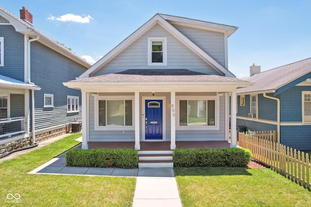 view of front of home with cooling unit, covered porch, and a front yard