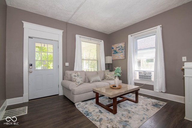 living room with cooling unit, a textured ceiling, dark hardwood / wood-style floors, and a healthy amount of sunlight