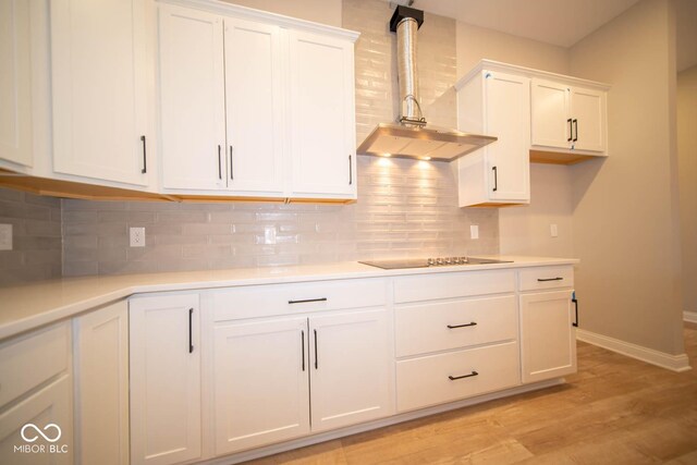 7936 Beaumont Green Pl, Indianapolis, IN 46250 - kitchen with black electric cooktop, wall chimney exhaust hood, white cabinets, and light wood-style flooring