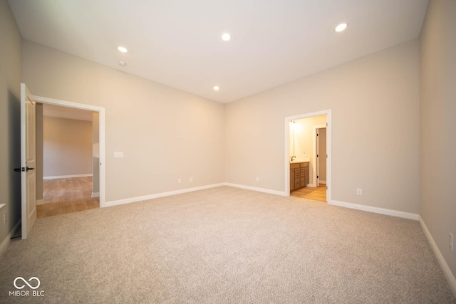 unfurnished bedroom with ensuite bath and light carpet