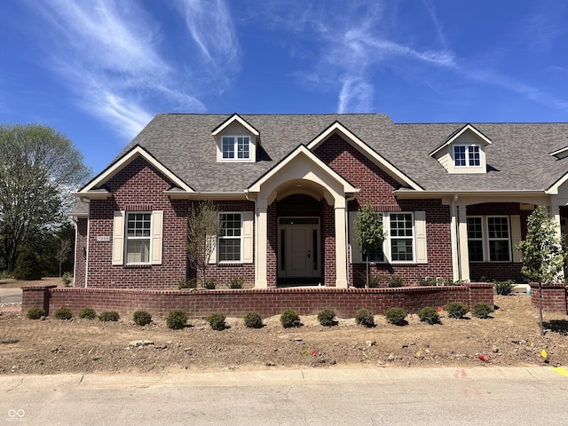 view of front facade with brick siding and roof with shingles