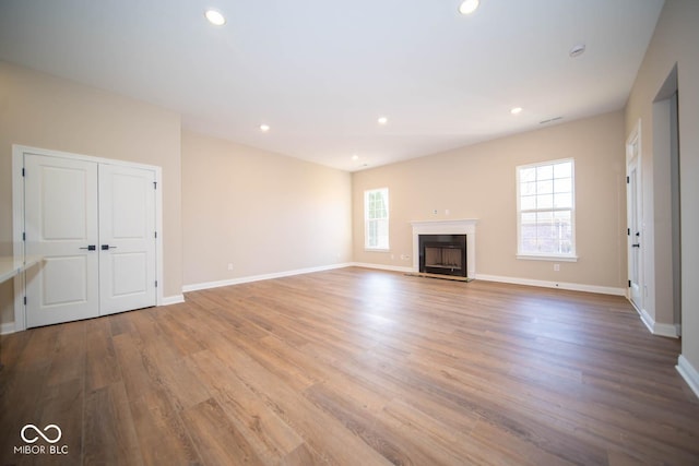 unfurnished living room featuring plenty of natural light and hardwood / wood-style flooring