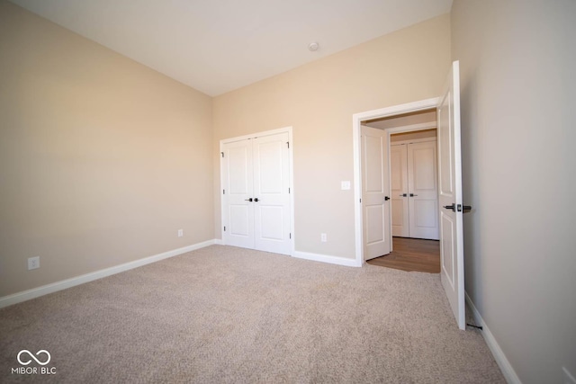 unfurnished bedroom with carpet flooring, a closet, and lofted ceiling