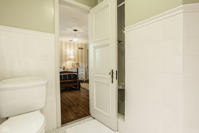 bathroom featuring tile walls and toilet